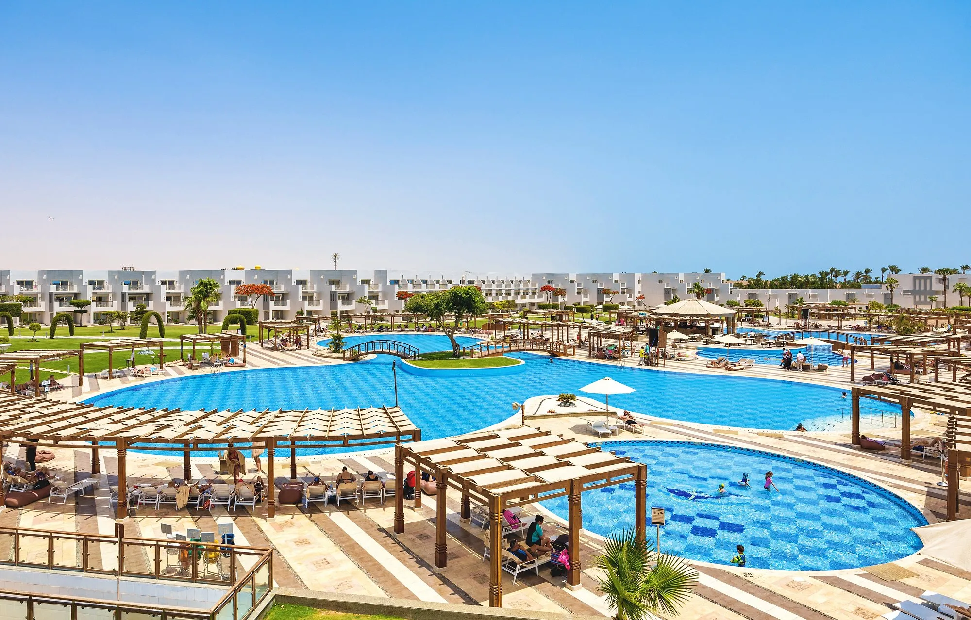 Grote zwembaden met geblokte bodem, eilandje en pergola's, kamers op de achtergrond, SUNRISE Crystal Bay Resort in Hurghada